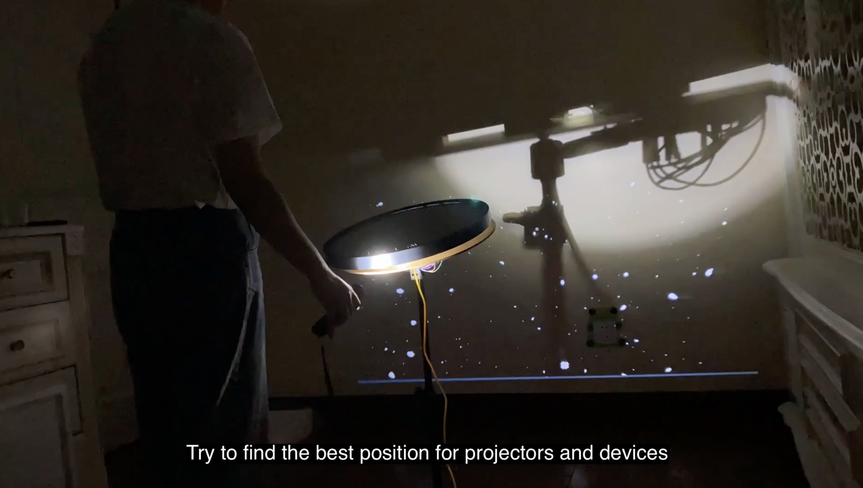 A person standing in front of an installation, testing or interacting with light elements.